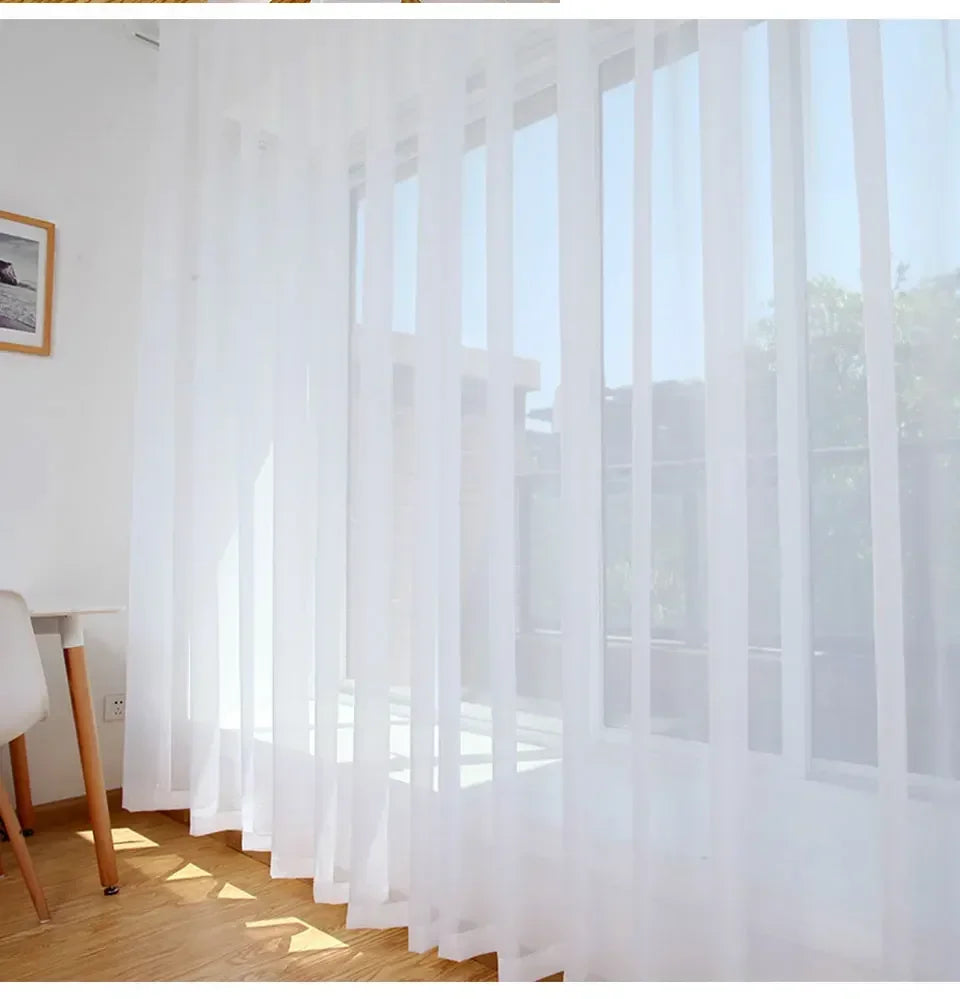 Durchscheinende weiße Tüllvorhänge hängen senkrecht und diffusen natürliches Licht durch ein Fenster.