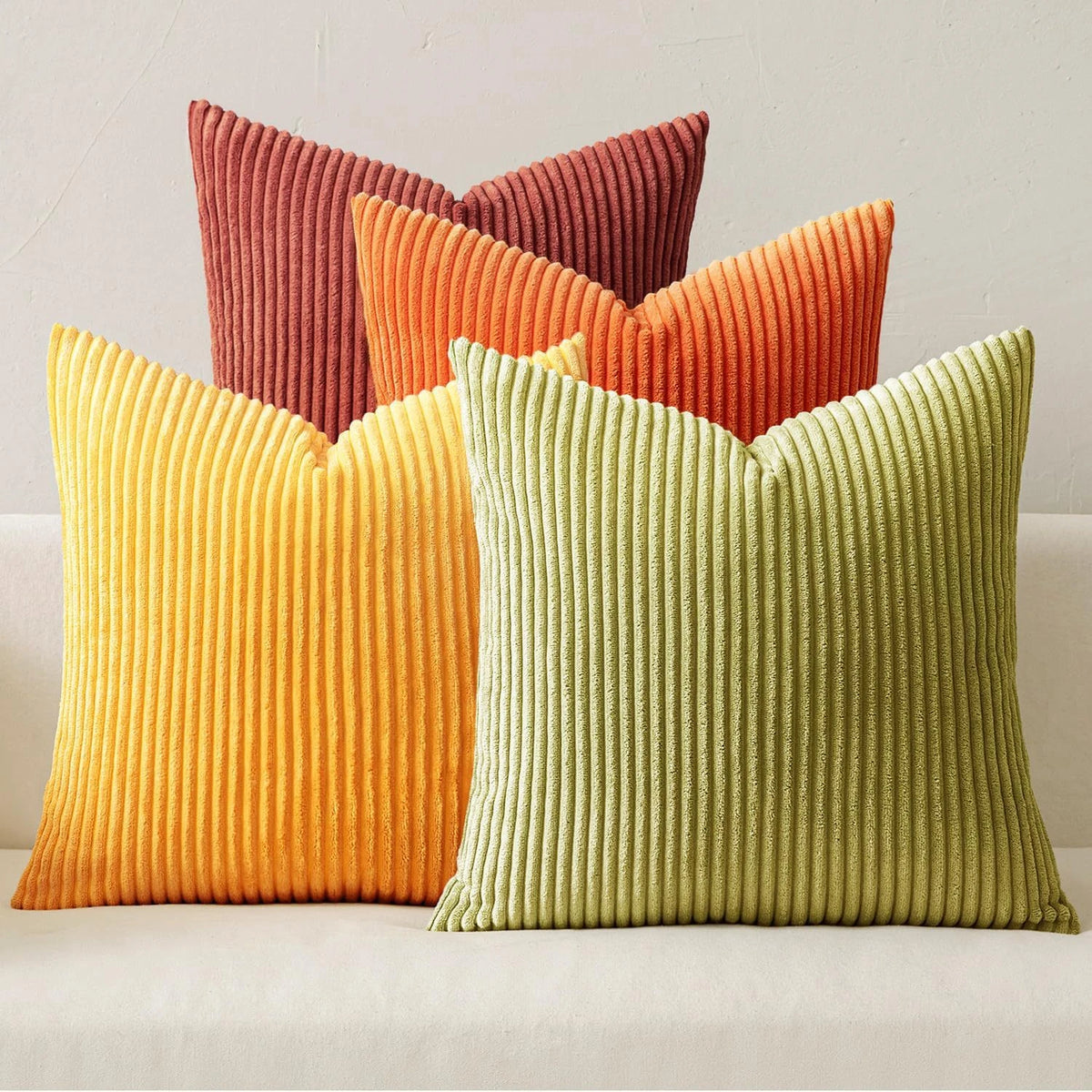 A collection of nine textured corduroy throw pillows in shades of orange, terracotta, and lime green.
