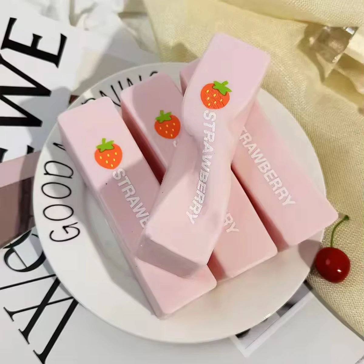 Pink squishy butter fidget toys shaped like strawberries are displayed on a white plate.