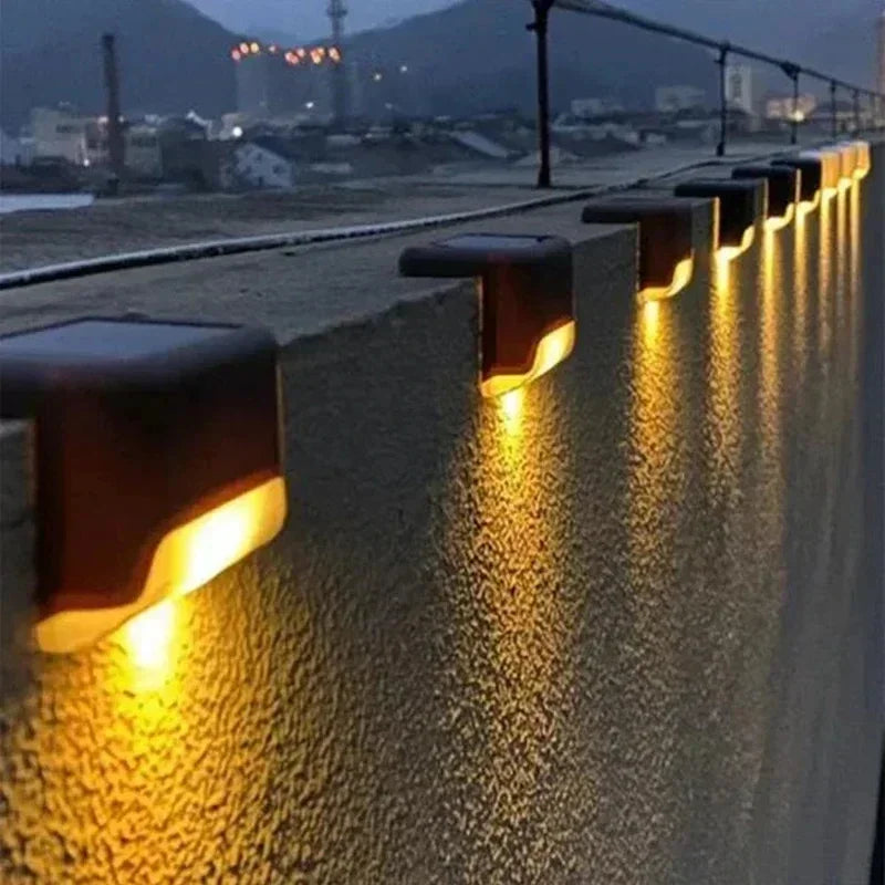 Row of solar powered LED step lights illuminating an outdoor pathway or deck at dusk.