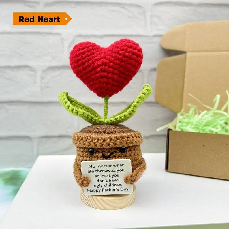 A handmade crochet red heart shaped doll with green leaves and a brown pot, decorated with a message for Father's Day.