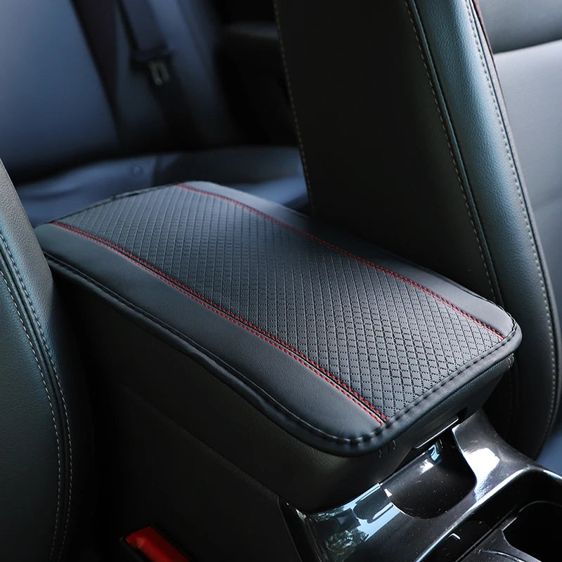 Black leather car armrest cover with a textured storage pad and red stitching.