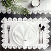 A white dinner plate set with linen hemstitch napkins and silverware displayed on a lace doily.