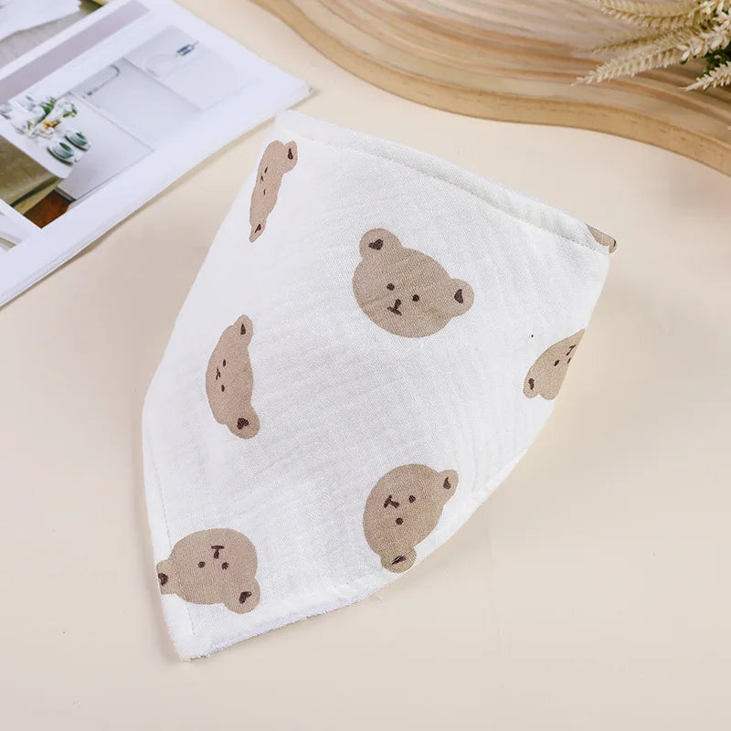 A white cotton baby bib featuring scattered brown bear-shaped patterns, shown on a light background.