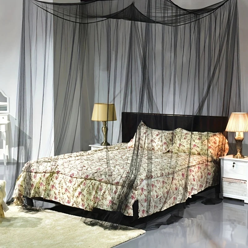 A bedroom featuring a bed draped with a sheer mosquito net and flowing fabric curtains.
