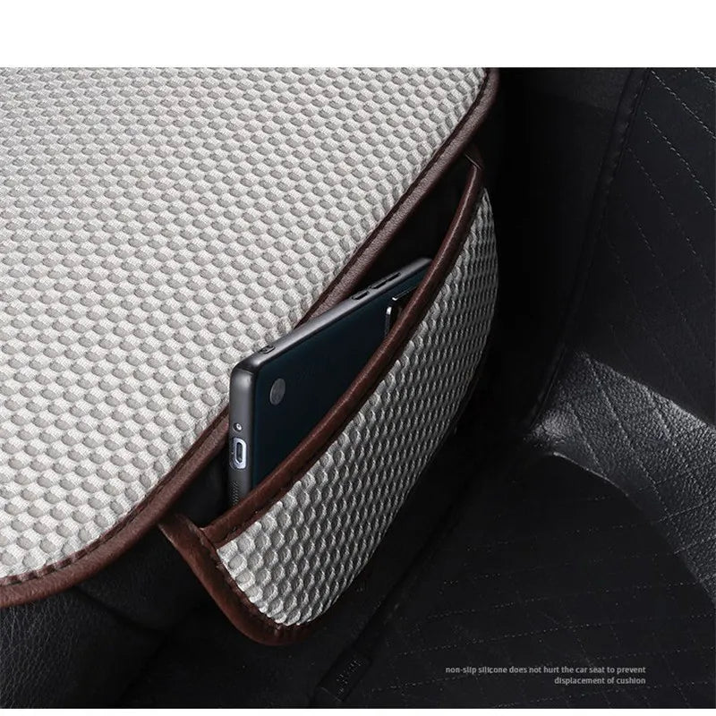 A dark smartphone is placed inside a brown leather car seat cushion with a textured gray fabric cover.