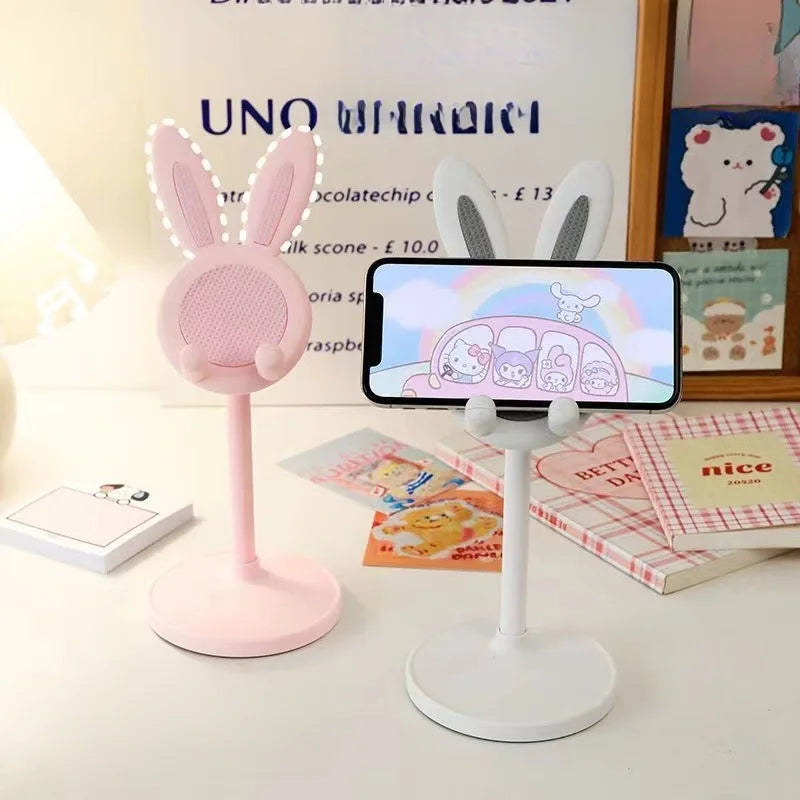 A pink rabbit mobile phone and tablet stand with a white base is shown on a white surface.
