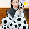 A woman holds a black and white football plush pillow against her chest.
