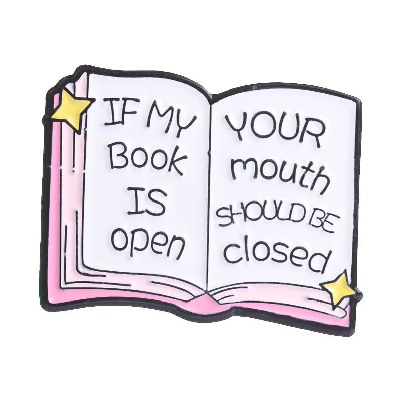 Enamel pin featuring an open book design with text If my book is open your mouth should be closed