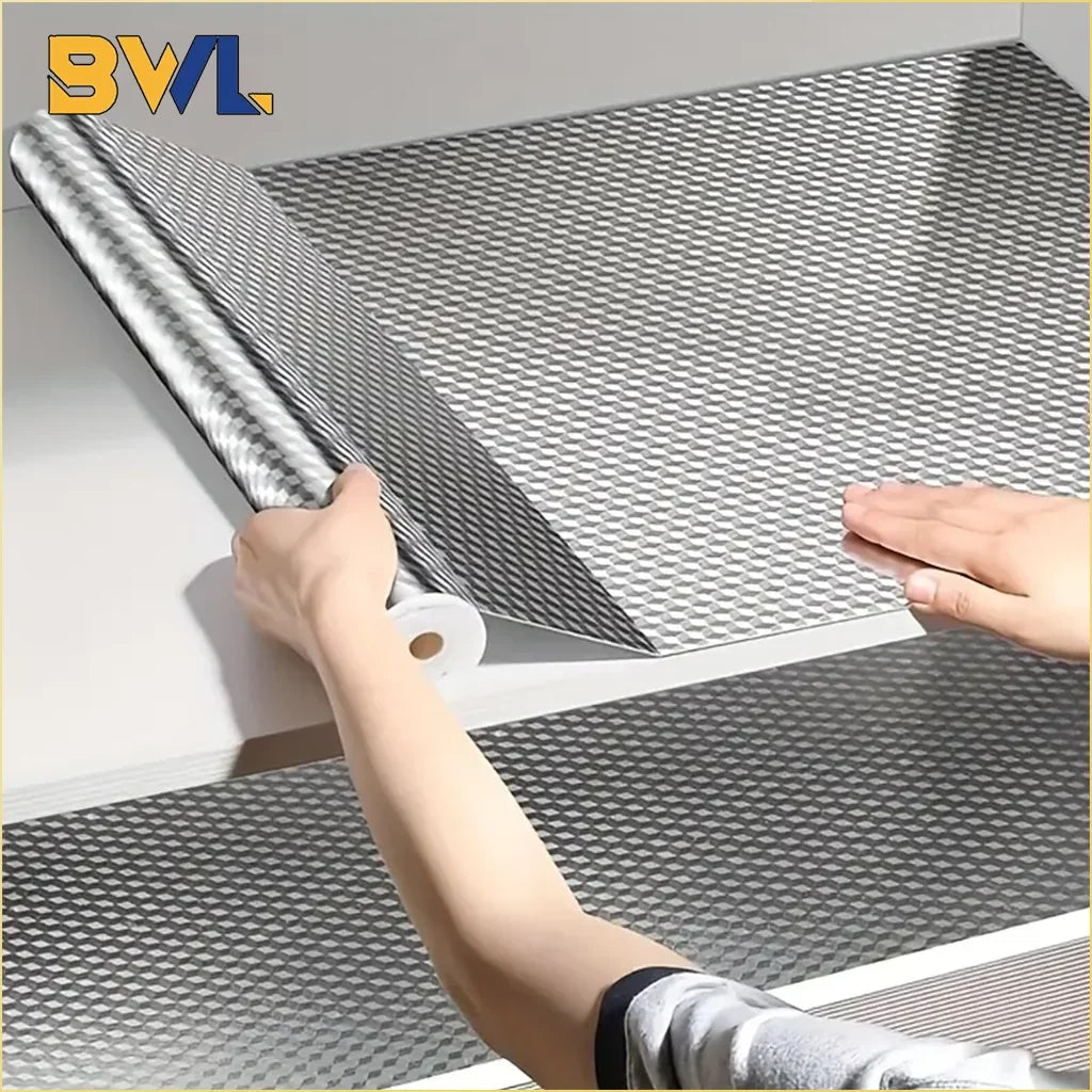 A hand is peeling a sheet of self-adhesive aluminum foil wallpaper liner from a white cabinet surface.