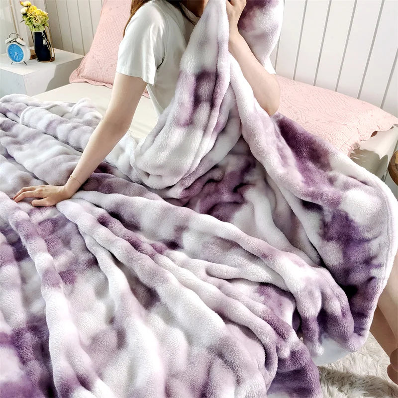 A person is wrapped in a gradient purple and white bubble fleece throw blanket on a bed.