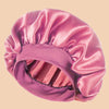 A pink satin wide brim shower cap folded and displayed against a light background.