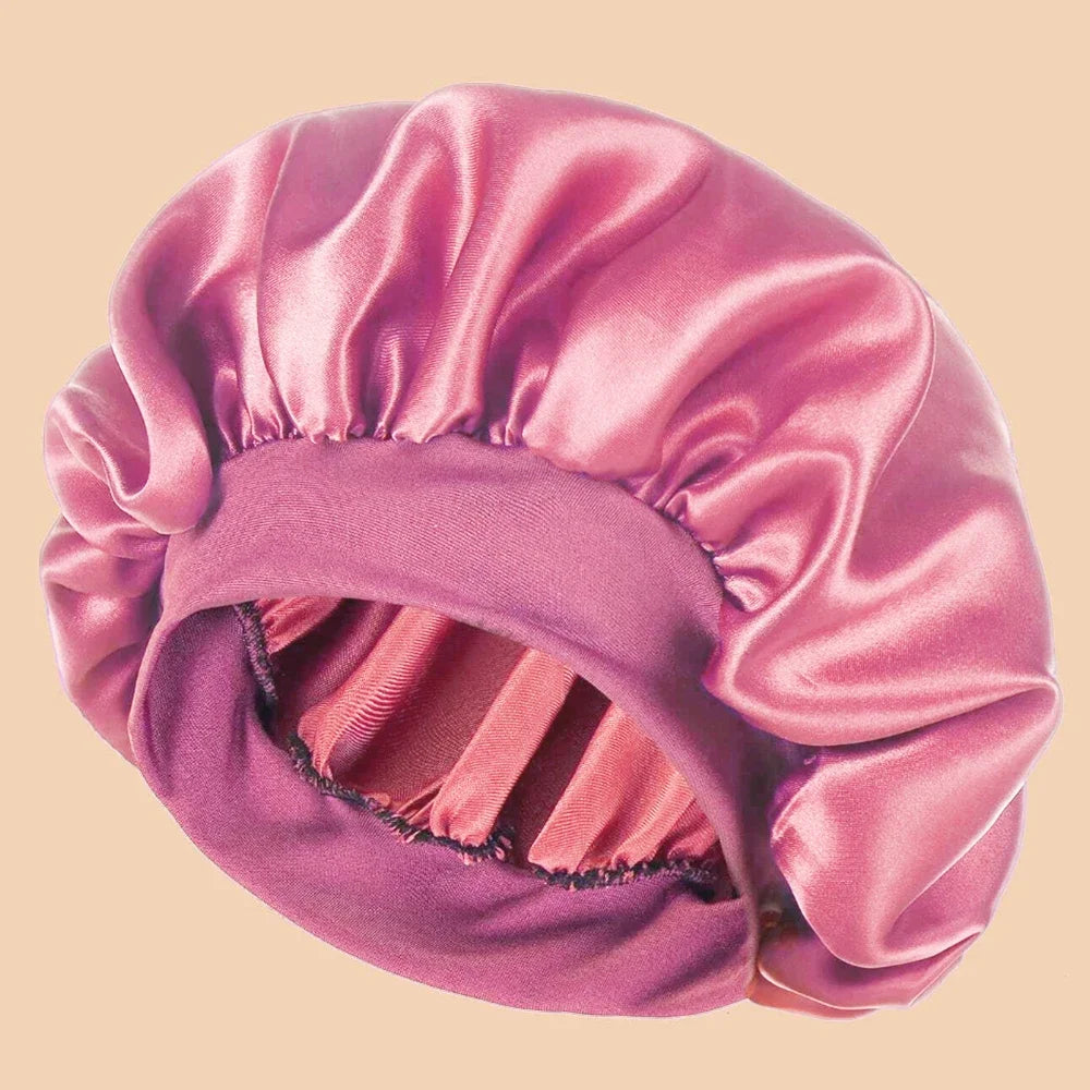 A pink satin wide brim shower cap folded and displayed against a light background.