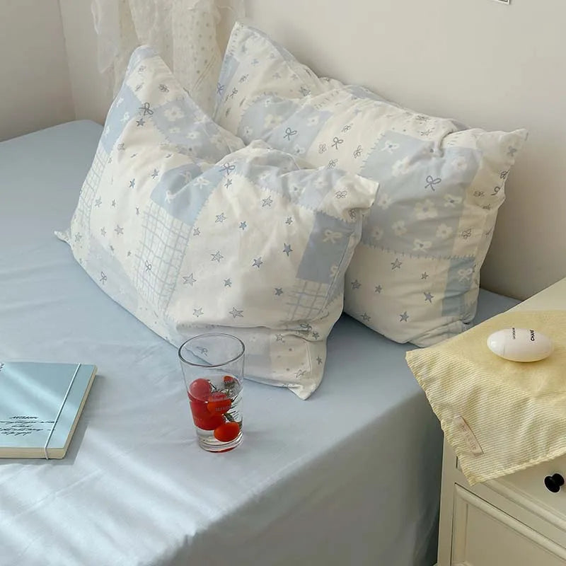 A light blue duvet cover set with two pillows featuring a white background and small blue floral patterns.