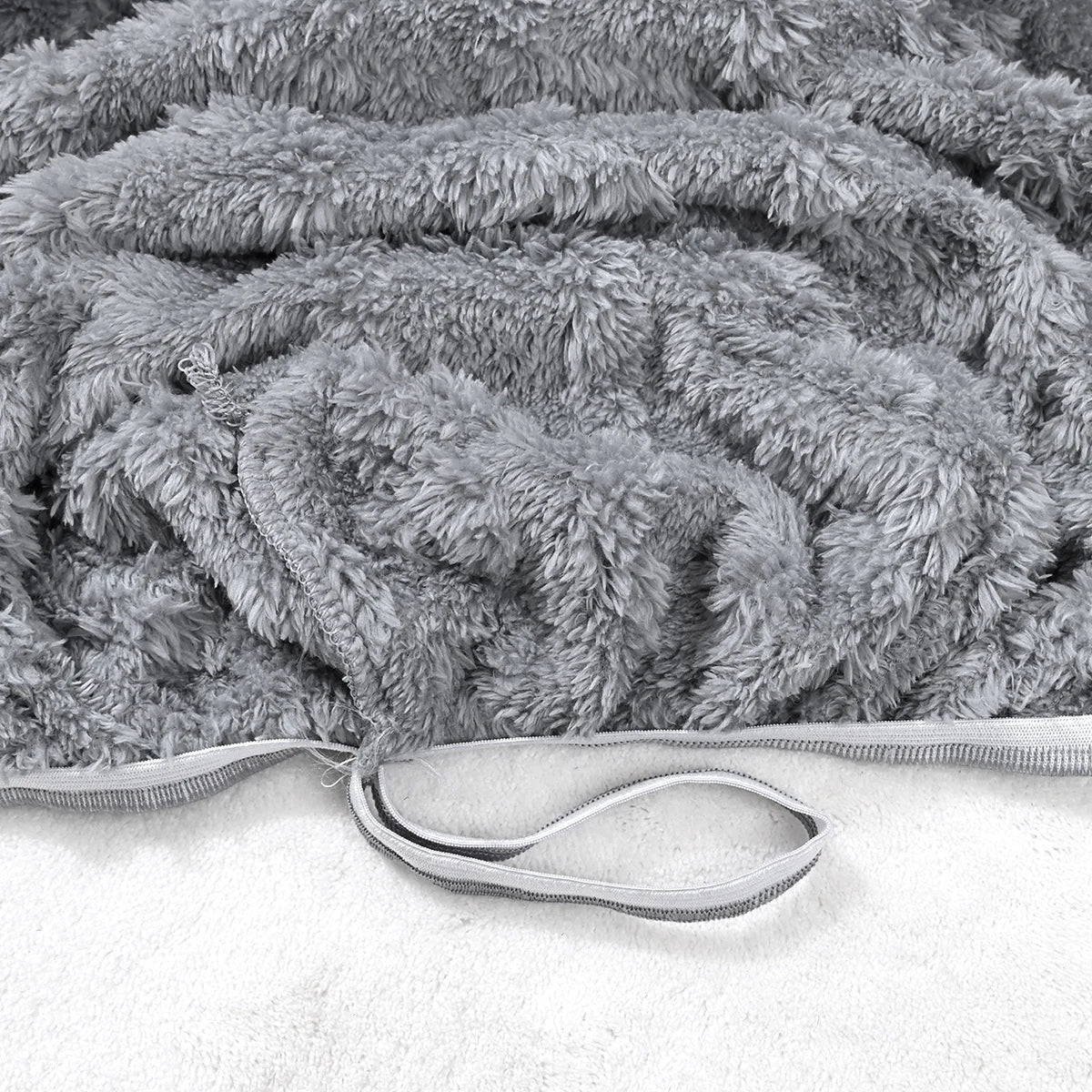 Gros plan d'une housse de canapé jacquard grise et duveteuse avec détail zippé.