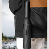 A black folding umbrella is shown hanging on a person's jacket, demonstrating its convenient to carry feature.