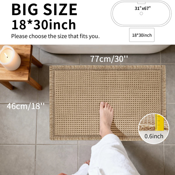 A close-up of a beige waffle weave bath mat being used by a person's foot, showing its texture and thickness.