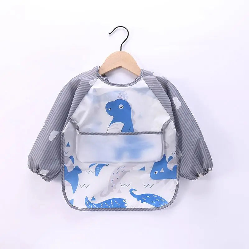 A waterproof long-sleeve baby feeding smock featuring a blue dinosaur design, displayed on a hanger.