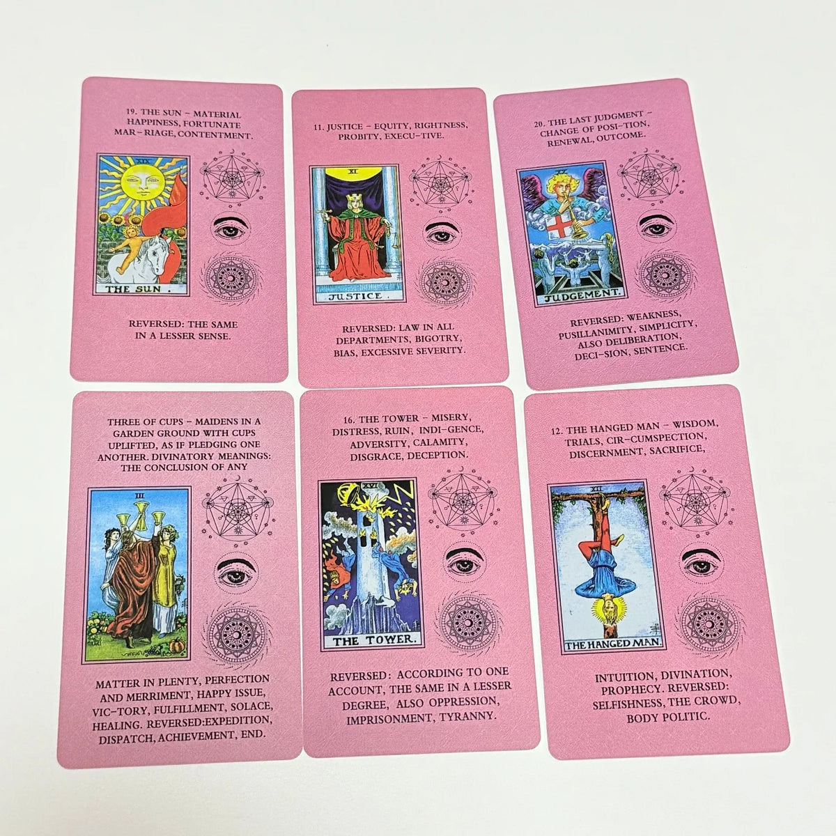 A set of pink Rider-Waite Tarot cards showing various cards like The Sun, Justice, and The Tower.