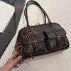 Dunkelbraunes Lederhandtasche mit Multi-Fächern und Messing-Hardware wird von einer Hand gehalten.