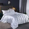A luxurious white silky duvet cover set displayed on a bed with gold accents and dark gray curtains.