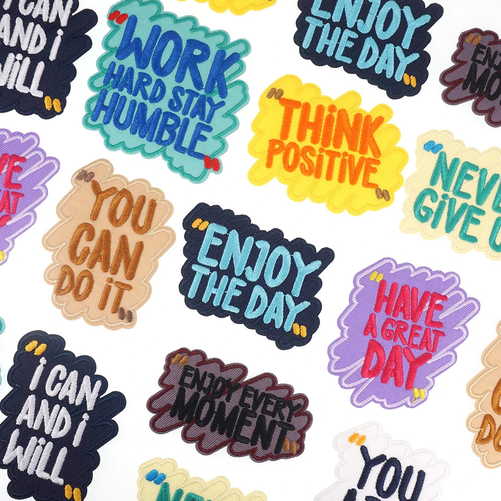A collection of colorful embroidered humorous iron-on patches featuring phrases like Work Hard Stay Humble and Enjoy The Day.