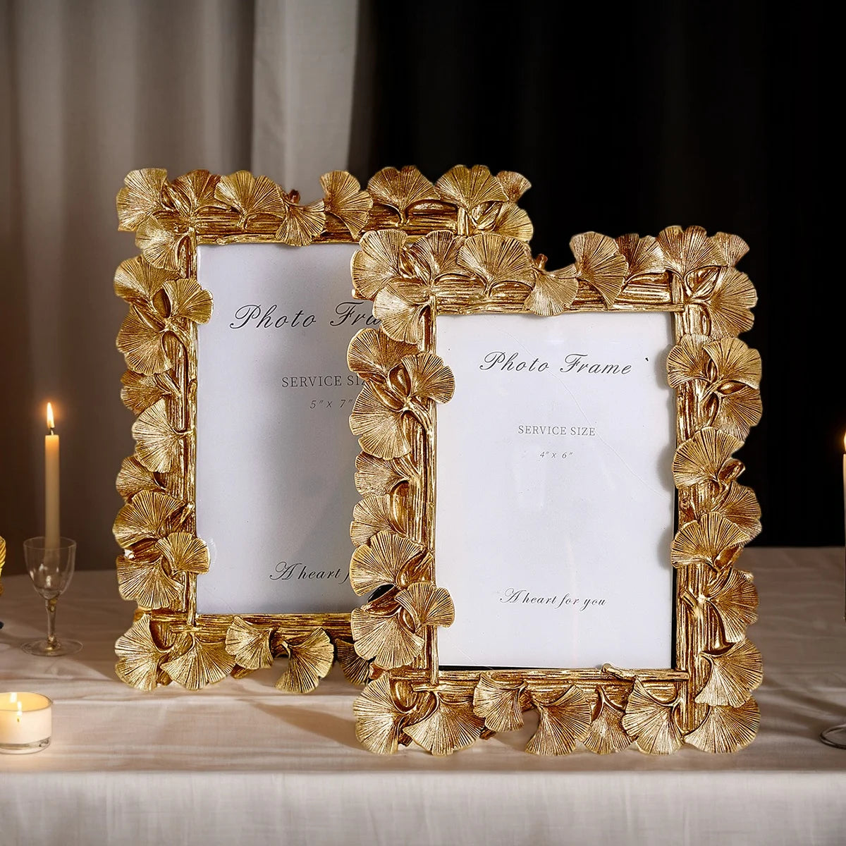 An elegant golden ginkgo leaf resin photo frame with a white mat displayed on a table.