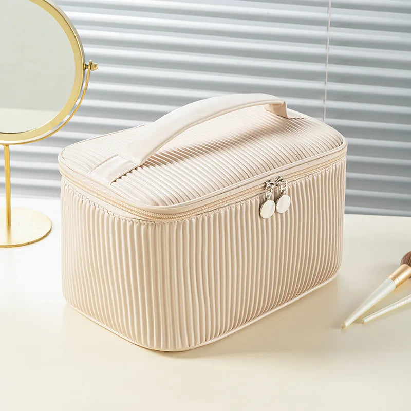 A beige striped PU leather makeup bag set with a lid and decorative hardware resting on a white surface.