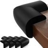 A set of black soft baby corner guards for furniture safety shown on a wooden surface.