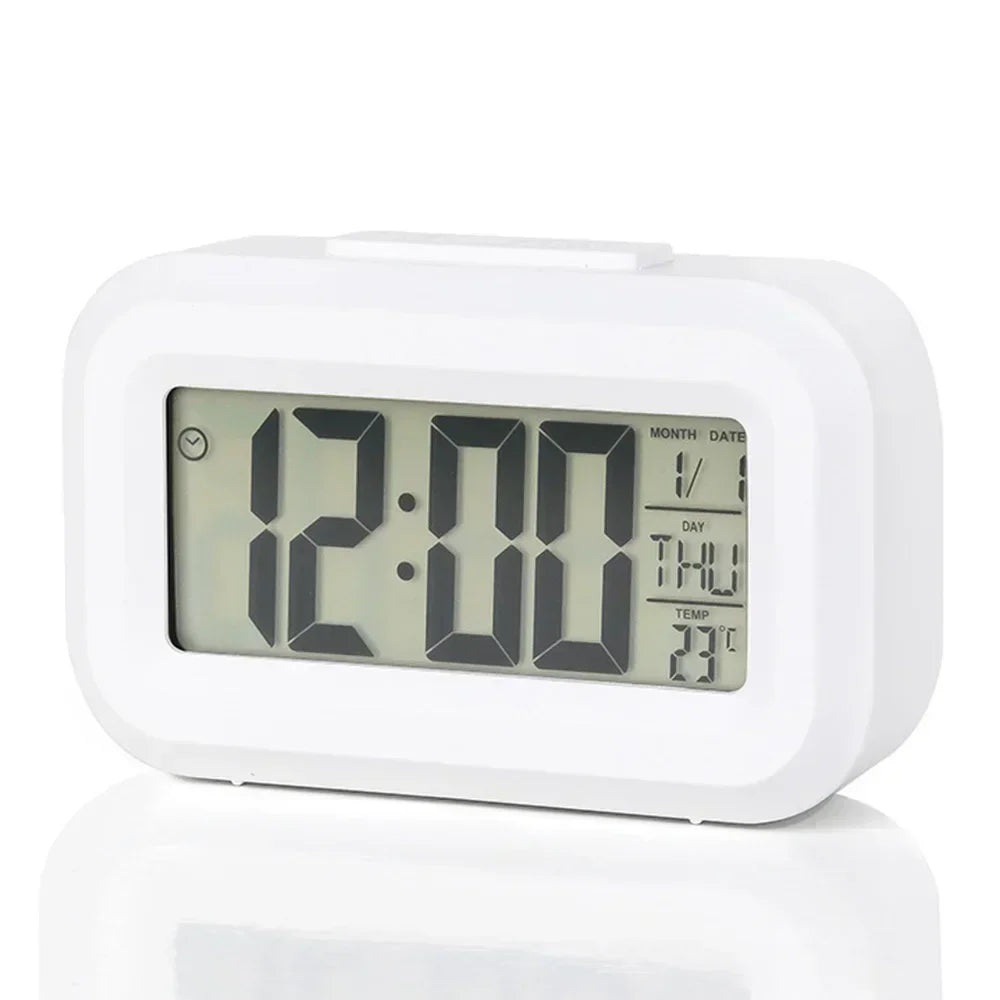 A white compact LED digital alarm clock with a display showing 12:00 and temperature settings.