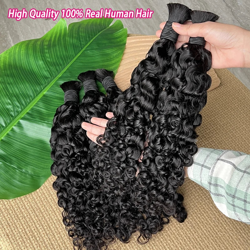 Ein Bündel schwarzer lockiger Haarextensions neben einem grünen Blatt auf einer Holzoberfläche.