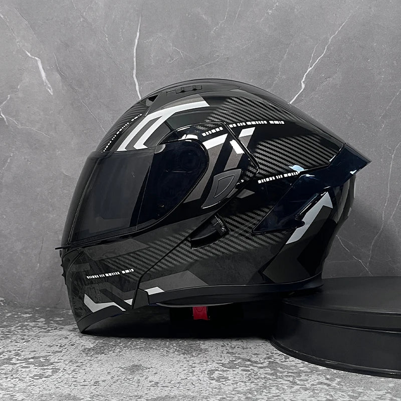 A black modular flip-up motorcycle helmet is displayed against a gray textured wall.