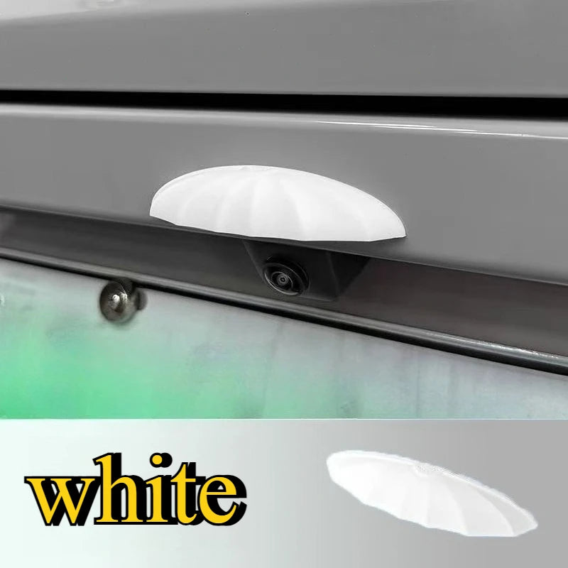 A white rain shield for a universal car rear camera is shown mounted on a vehicle's exterior.
