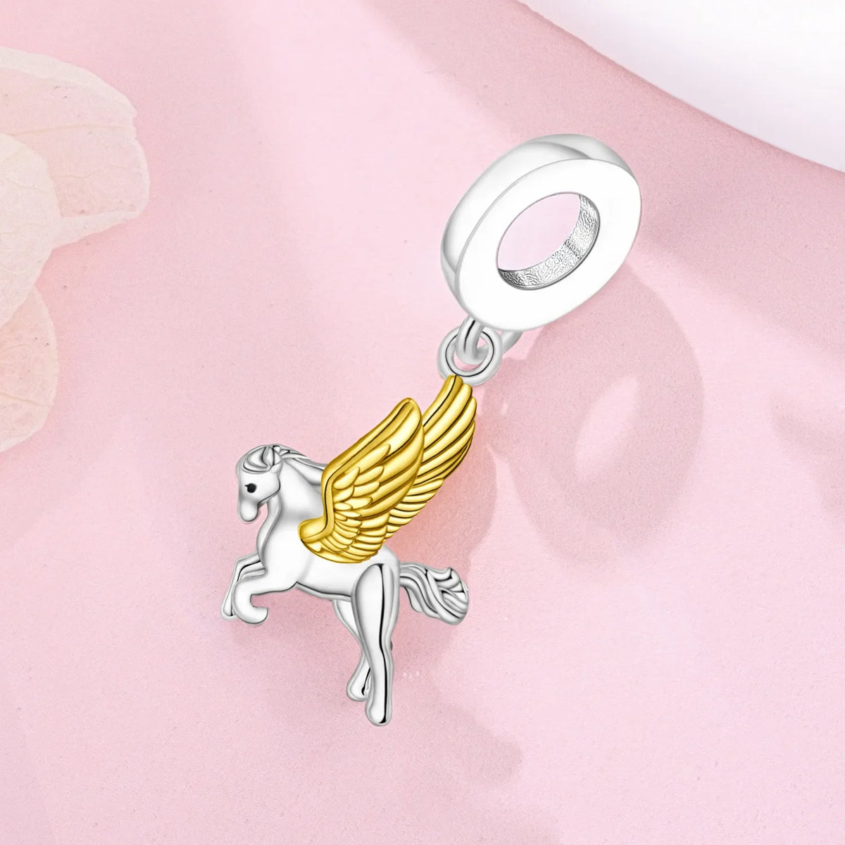 Silver unicorn pegasus charm with gold wings and sparkling crystals on a pink background