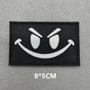 Black embroidered patch featuring a white angry face design with hook and loop backing