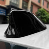 Black sleek shark fin antenna cover resting on a white surface.