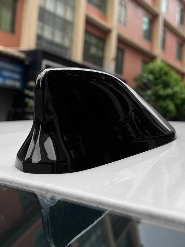 Black sleek shark fin antenna cover resting on a white surface.