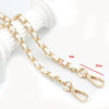 Gold-colored universal chain strap for bags and phone cases shown next to a white object.