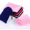 A stack of pink and purple drawstring storage bags next to a dark blue bag.