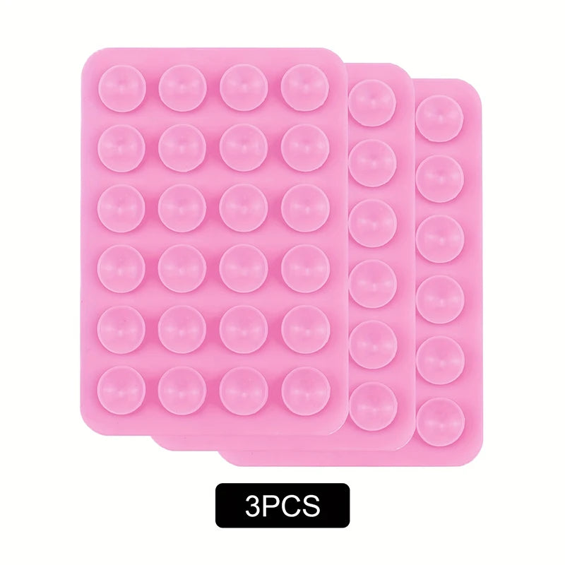 A pack of three pink reusable silicone suction phone mounts with circular suction cups.