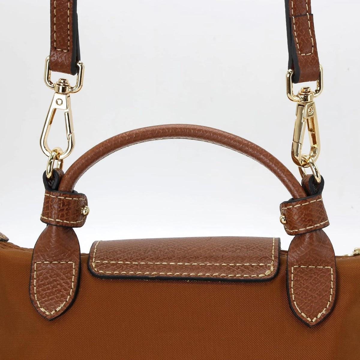 A brown leather shoulder strap with gold hardware is shown against a white background.