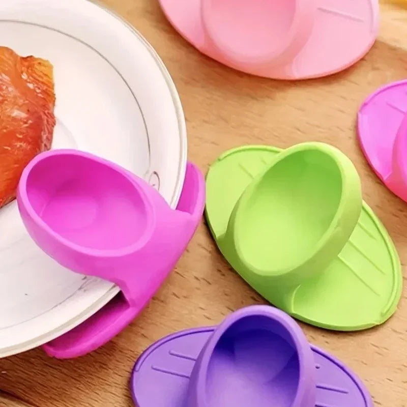 A collection of pink, green, and purple silicone finger covers for baking and cooking placed on a wooden surface.