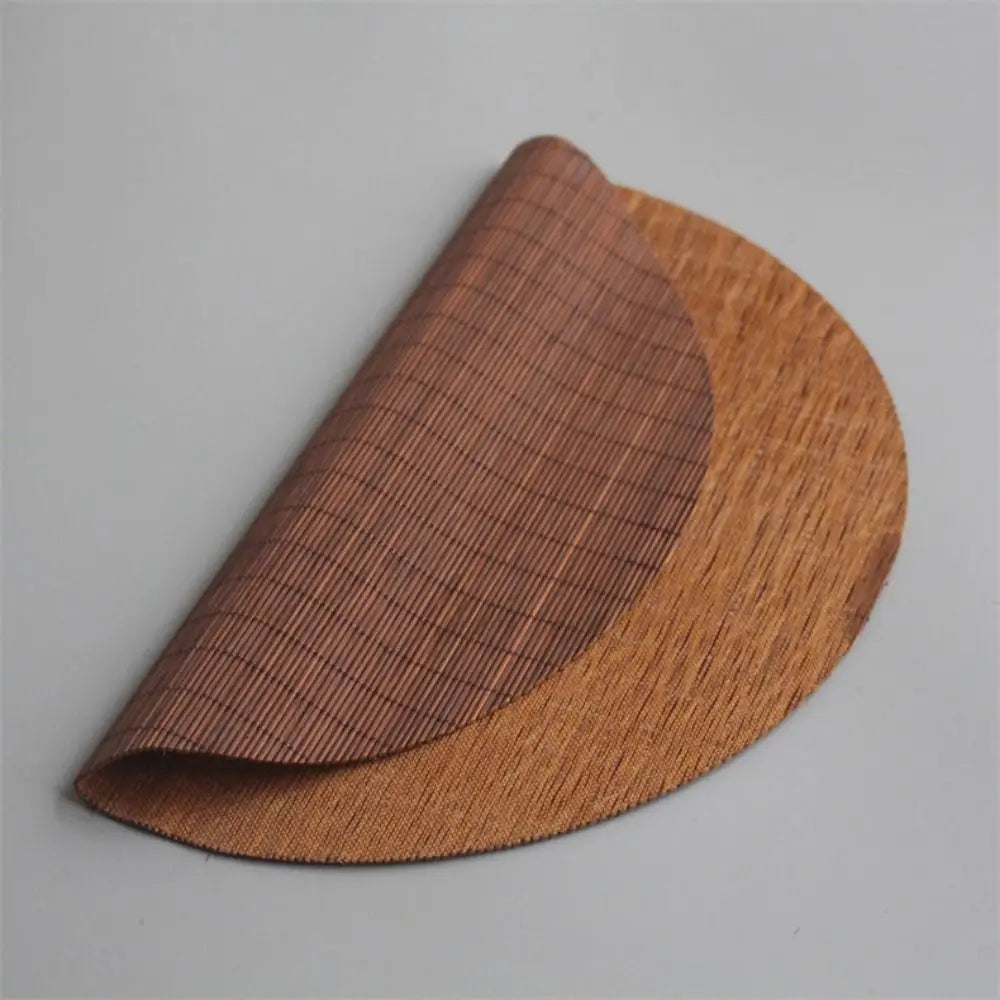 A curved, brown hand-woven bamboo tea mat showing a tight woven texture.