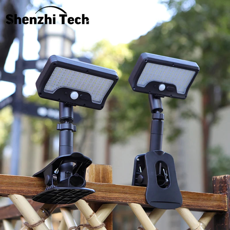 Two black solar-powered motion sensor outdoor lights mounted on a wooden railing.