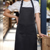 A woman wearing a black apron stands in a bright, indoor setting.