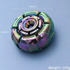 A close-up view of a metallic fidget spinner with iridescent purple and green accents, shown against a light blue background.