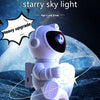 A white astronaut projector lights a starry sky on the ground, featuring 8 nebula modes and a Bluetooth speaker.