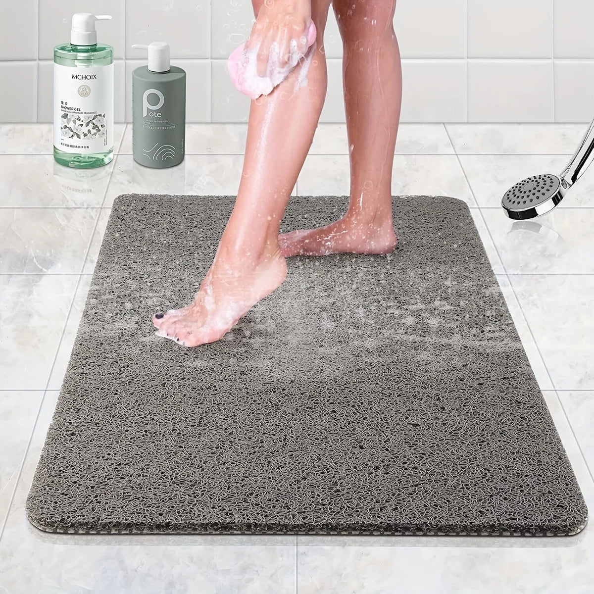 A person's legs are standing on a gray absorbent bathroom floor mat while using body wash.