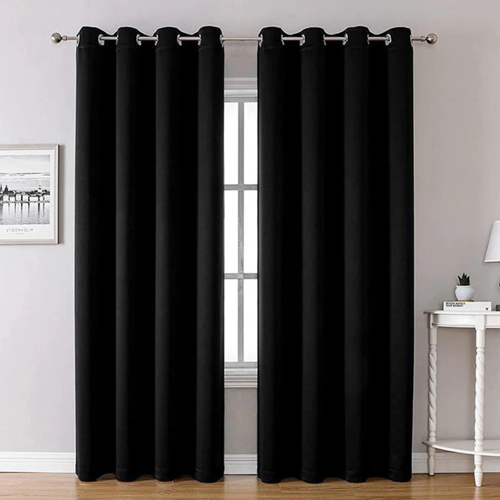 Rideaux thermiques noirs en blackout accrochés à une tringle près d'une fenêtre.