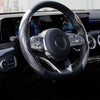 Close-up view of a black steering wheel with an ultra-thin carbon fiber cover and modern controls.
